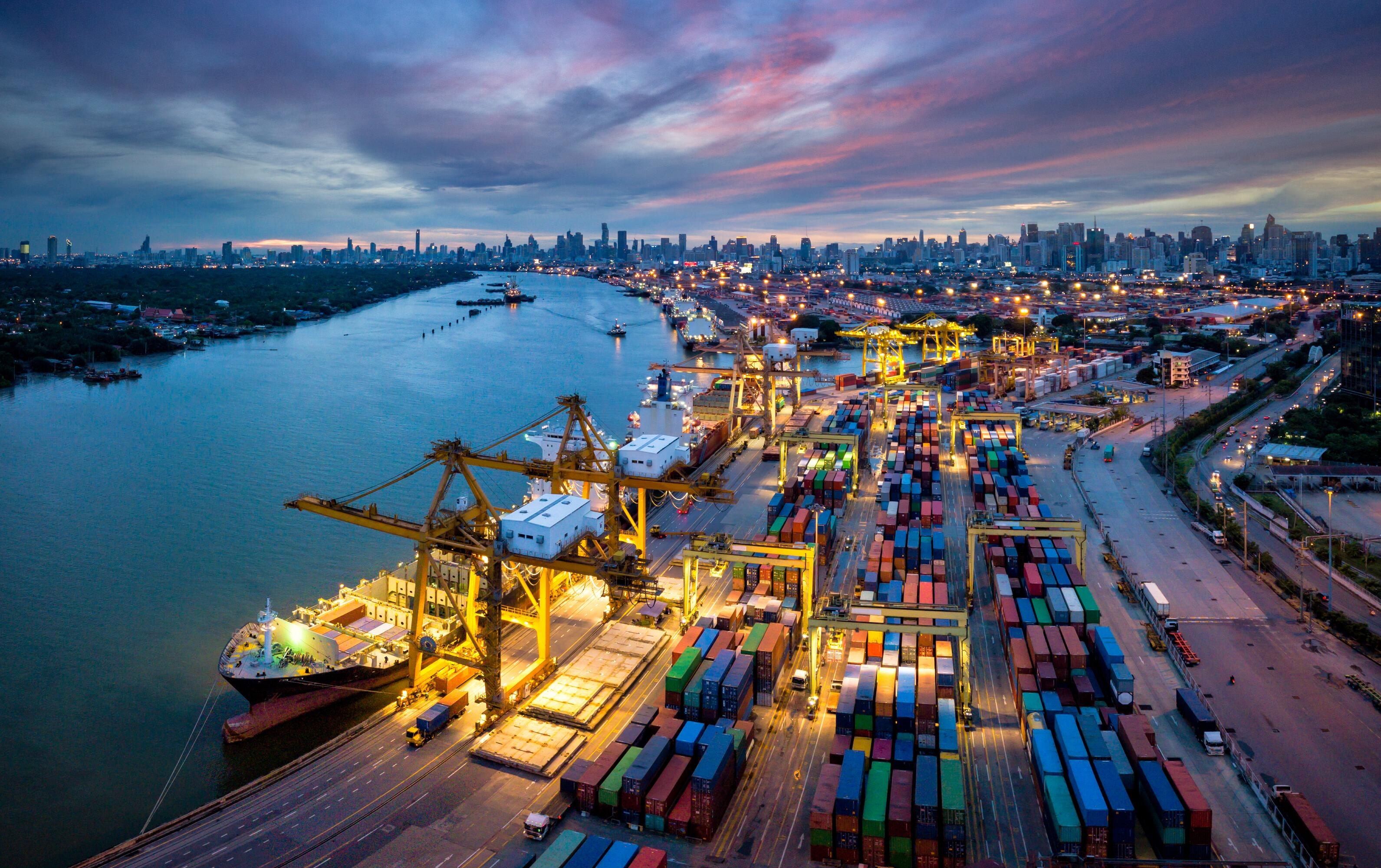 A bustling port at dusk, filled with vibrant shipping containers and illuminated cranes, symbolising the extensive global reach of the Flowflex brand. This image showcases Flowflex's capability to deliver plumbing components and HVAC solutions to customers around the world, highlighting the efficiency and reliability in their supply chain and distribution network.