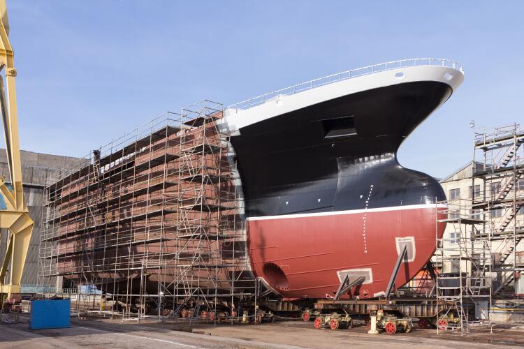 A large ship under construction in a shipyard, surrounded by scaffolding. This highlights the application of Flowflex fittings and valves in the marine industry, providing essential components for shipbuilding and maintenance.