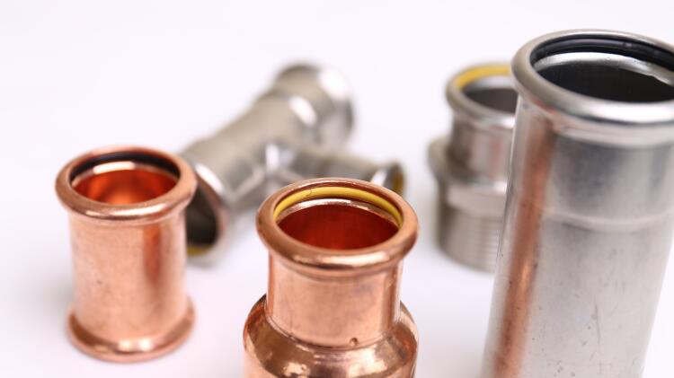 Close-up view of various Flowflex copper and stainless steel press fittings, illustrating their precise design and high-quality construction, used in plumbing and HVAC systems.