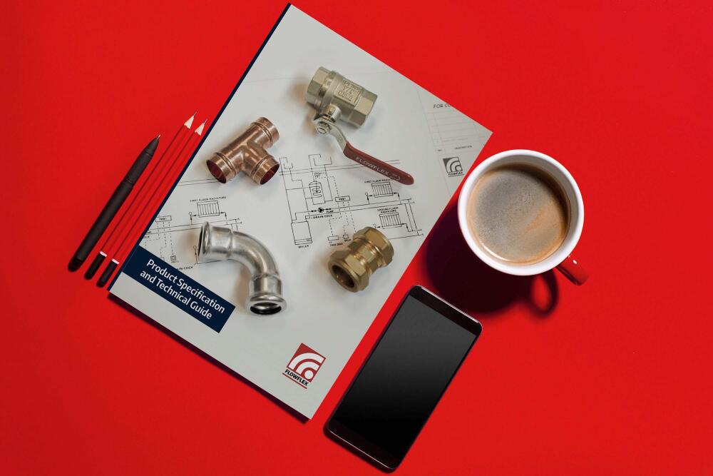 Flowflex product brochure titled “Product Specification and Technical Guide” is laid out on a red table. The brochure features technical drawings and product details, highlighting Flowflex’s range of products.