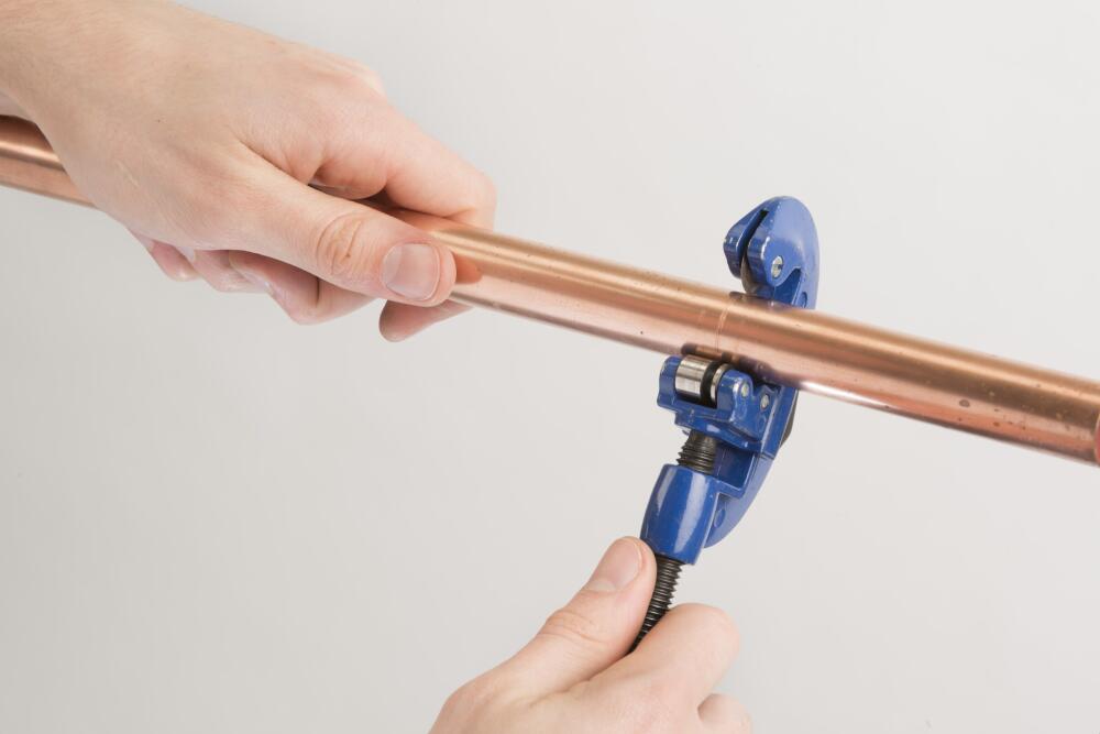 Image showing an installer accurately cutting his copper pipe to size