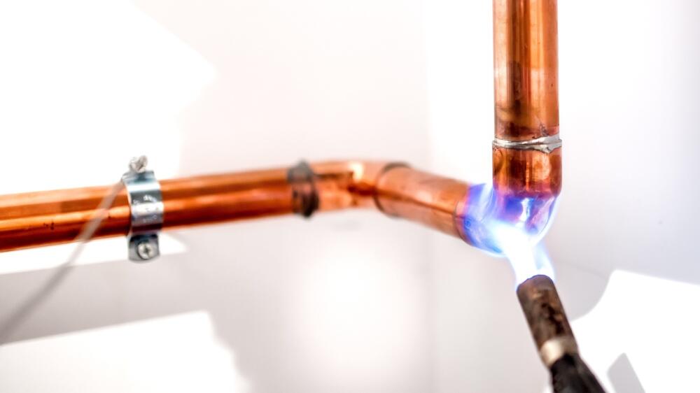 Copper pipe being soldered with a capillary fitting using a torch, showcasing Flowflex’s high-quality plumbing components for secure and reliable connections.